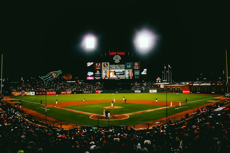 Exciting evening baseball game with fans at AT&T Park stadium under bright lights.
