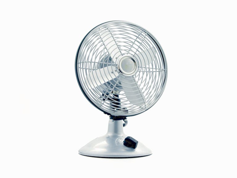 Close-up of a classic electric desk fan against a white background, showcasing retro design.